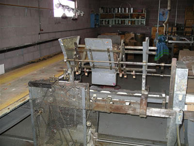 Shaft hopper - formerly used as a hopper for wooden broomstick handles - feeds shafts onto lacquering conveyor belt